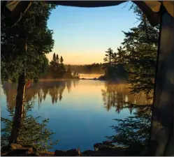  ?? Tribune News Service/dreamstime ?? Looking out through the doorway of a tent onto morning mist over Crescent Lake in Minnesota’s Superior National Forest.