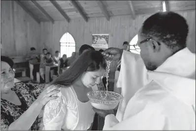  ?? AP/ESTEBAN FELIX ?? Priest Claude Yves Dilayen baptizes a woman earlier this month in the Mapuche community of Newen Wenu Chau in Temuco, Chile.