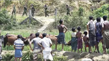  ?? DOMINIQUE FAGET/AFP ?? Rohingya refugees in Jalpatoli refugee camp in the no-man’s land area between Myanmar and Bangladesh watch as Myanmar soldiers patrol on the other side of the border on September 16.