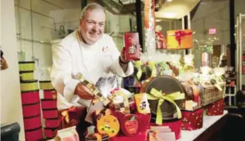  ??  ?? In this file photo, Jacques Torres, who sells his well-known and high-end chocolate and other food at eight locations in New York and online, assembles a gift basket at his flagship store in New York.—AP