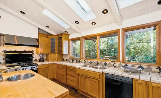  ??  ?? Above: The kitchen has a commercial range and exhaust hood, skylights and display cabinets. Below left: The landscape around the home includes brick stairs and built-in planter boxes. Below right: The master bathroom includes a soaking tub, exterior...