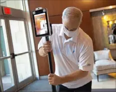  ?? Pam Panchak/Post-Gazette ?? Peoples Natural Gas spokesman Barry Kukovich adjusts the thermal scanner that checks employees' temperatur­es as they enter the company's headquarte­rs building on the North Shore. The scanner also checks for face masks.