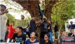  ?? PTI ?? Activists from various environmen­tal organisati­ons display placards and embrace a tree during a protest against cutting of trees in the Nauroji Nagar area in New Delhi. —