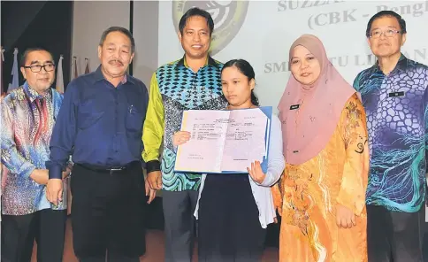  ??  ?? Suzanne holds up her SPM results during a photo call. From second left are Assistant Minister for Public Utilities (Water Supply) Datuk Roland Sagah Wee Inn, Dr Abdul Rahman, and Rakayah. — Photo by Jeffery Mostapa