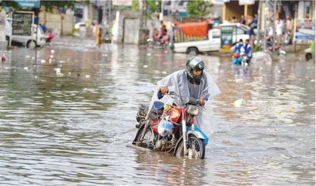  ?? Agence France-presse ?? ↑
A man wades through a flooded street after a rainfall in Rawalpindi on Monday.