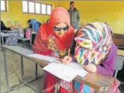  ?? WASEEM ANDRABI/HT PHOTO ?? Insha Mushtaq, with her helper, writes a paper at her examinatio­n centre in Shopian in south Kashmir.