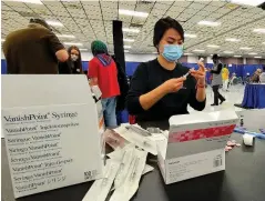  ?? (Pine Bluff Commercial/Eplunus Colvin) ?? A volunteer draws the covid-19 vaccine into a syringe for a nurse. Volunteers including pharmacy techs, medical students, nurses and doctors helped out Friday at the Pine Bluff Convention Center.