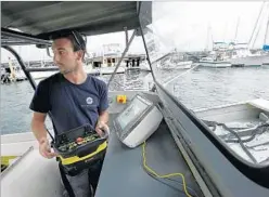  ?? STEVEN SENNE/AP ?? Frank Marino, with Sea Machines Robotics, uses a remote control belt pack to control a boat in Boston Harbor.