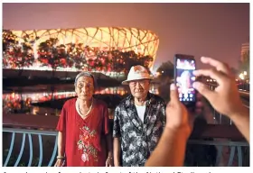  ??  ?? A couple posing for a photo in front of the National Stadium, known as the Bird’s Nest, which was built for the 2008 Beijing Olympic Games.