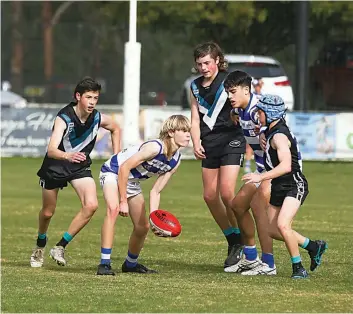  ?? Photograph­s by ALYSSA FRITZLAFF. ?? James Welford looks to handball clear of the pack for Neerim in the under 16s.