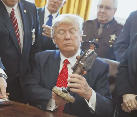  ?? AP PHOTO ?? CASTING A WATCHFUL EYE: President Trump looks at a figurine given to him by a group of county sheriffs yesterday in the Oval Office.