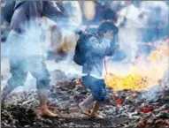  ?? KIM KYUNG-HOON / REUTERS ?? A boy overcomes his fear as he walks barefoot over coals with an adult guiding him during the fire-walking festival Hiwatari Matsuri at Mount Takao in Tokyo on March 13. The Takaosan Yakuoin Buddhist Temple said about 1,500 Japanese worshipper­s walked barefoot with Buddhist monks over coals to pray for safety and an end to the COVID-19 pandemic.