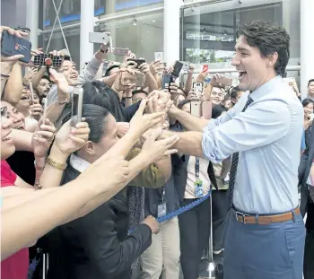  ?? ADRIAN WYLD/THE CANADIAN PRESS ?? Prime Minister Justin Trudeau shakes hands as he walks through a building’s lobby in Manila, Philippine­s, on Monday.