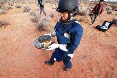  ?? JAXA via AP ?? ABOVE:
■ In this photo provided by the Japan Aerospace Exploratio­n Agency, a member of JAXA retrieves a capsule dropped by Hayabusa2 in Woomera, southern Australia, on Sunday. A Japanese capsule
carrying the first samples of asteroid subsurface shot across the night atmosphere early Sunday before successful­ly landing in the remote Australian Outback, completing a mission to provide clues to the origin of the solar system and
life on Earth.