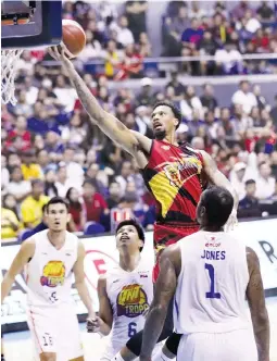  ?? (PBA Images) ?? San Miguel import Chris McCullough scores off TNT KaTropa’s Troy Rosario, left, Don Trollano and Terrence Jones, right, during Game 4 of the PBA Commission­er’s Cup Finals Sunday at the Smart Araneta Coliseum.