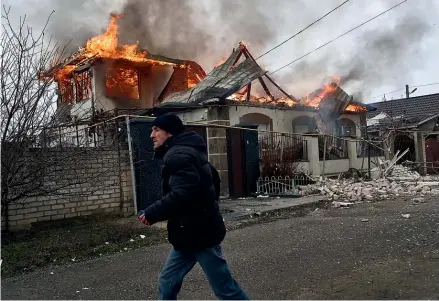  ?? AP ?? A resident runs past a burning house hit by Russian shelling in Kherson, Ukraine on Orthodox Christmas Eve yesterday. Russia has announced a 36-hour ceasefire for the holiday, but Ukrainian and Western officials have scorned the move as a ploy to allow Vladimir Putin’s forces to regroup.