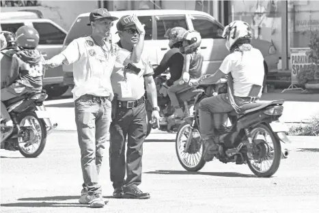  ?? MACKY LIM ?? TRAFFIC TRAINEE. A traffic enforcer-trainee mans the intersecti­on of Matina Crossing in Davao City while being observed by a City Transport and Traffic Management Office personnel during their field training Tuesday morning.