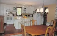  ??  ?? The modern kitchen was fitted by a company in Magog. The teak table is modern. The fiddle back chairs are antiques.