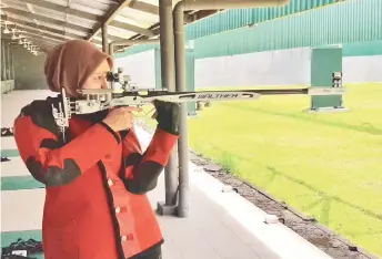  ??  ?? Aisyah aims for the bull’s eye during training at the Sarawak Shooting Range in Petra Jaya last Saturday.