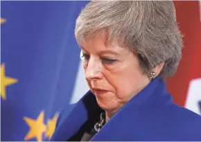  ?? ALASTAIR GRANT/AP ?? British Prime Minister Theresa May walks past the EU flag at the conclusion of a summit in Brussels on Sunday. European Union leaders signed off on an agreement on Britain’s departure from the bloc next year.