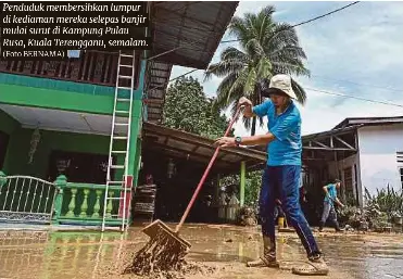  ?? (Foto BERNAMA) ?? Penduduk membersihk­an lumpur di kediaman mereka selepas banjir mulai surut di Kampung Pulau Rusa, Kuala Terengganu, semalam.