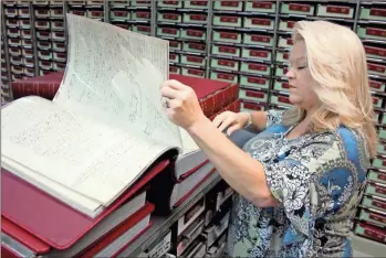  ?? Jeremy stewart ?? Polk County Superior Court Clerk Stacie Baines flips through one of the newly-restored deed books in the records archives of the county courthouse that dates back to 1897. Kofile Technologi­es was contracted to take all of the county’s deed books and scan them for easier access.