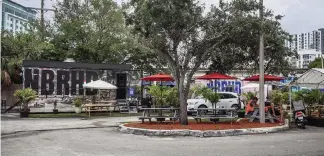  ?? CARL JUSTE cjuste@miamiheral­d.com ?? Delivery drivers and robots pick up food from mobile kitchens set up in a Brickell parking lot on Tuesday. A company called REEF wants to operate more such kitchens on vacant land across the city.
