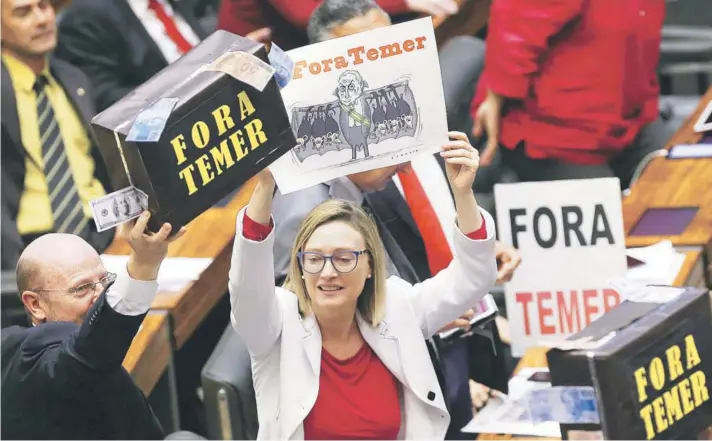  ??  ?? ► Diputados de la oposición se manifiesta­n contra el Presidente Michel Temer durante la votación de ayer en la Cámara Baja, en Brasilia.