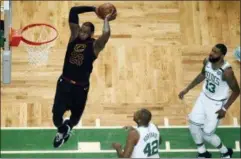  ?? CHARLES KRUPA — ASSOCIATED PRESS ?? Cavaliers forward LeBron James soars en route to a dunk in front of Celtics forward Al Horford, center, and forward Marcus Morris during the first half of Sunday’s Eastern Conference finals game in Boston.