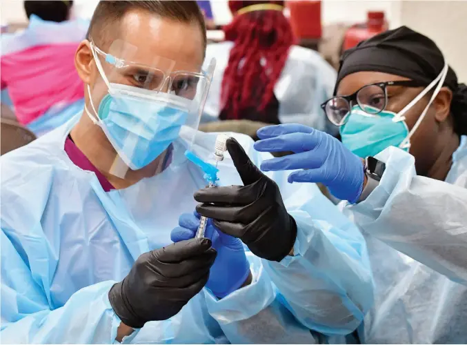  ??  ?? Western University of Health Sciences master nursing student Mark Sandoval (left) prepares a dose of the COVID-19 vaccine for a recipient at the SBCO—HR Test Center in San Bernardino, Calif. as he is assisted by Registered Nurse Sandria Braziel. (Photo by Will Lester/inland Valley Daily Bulletin/scng)