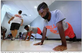  ?? (Arkansas Democrat-Gazette/Thomas Metthe) ?? Little Rock Hall’s Senterious Gaither (right) works out with teammates Thursday at the school. Players and coaches wearing masks and social distancing are part of offseason workouts as high school football teams prepare for the upcoming season.