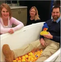  ?? PAUL POST — PPOST@DIGITALFIR­STMEDIA.COM ?? Adam Zima, right, of Capitol District Supply, tries out a Kohler bathtub complete with rubber duckies as co-workers Adrienne Petroski, left, and Kristin Sica, center, look on.
