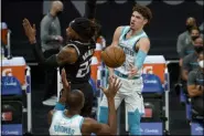  ?? THE ASSOCIATED PRESS ?? Charlotte Hornets guard LaMelo Ball (2) passes the ball around Sacramento Kings center Richaun Holmes (22) to teammate Bismack Biyombo during the first quarter of an NBA basketball game in Sacramento, Calif., Sunday, Feb. 28, 2021.