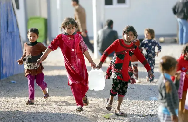  ?? — AFP file ?? Iraqi children carrying jerrycans of water. The region is already facing a severe water crisis, and with temperatur­es expected to rise in coming years, the problem could get worse.