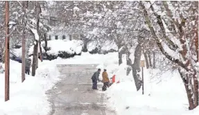  ?? MARK STOCKWELL/AP ?? Neighbors dig out a driveway Monday on Rockhill Street in Foxboro, Mass., after the area received well over a foot of snow.