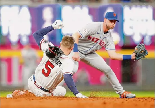  ?? Todd Kirkland / Getty Images ?? Atlanta’s Freddie Freeman beats the tag of New York’s Jeff Mcneil for a double in the fifth inning, one of the Braves’ 20 hits Wednesday.