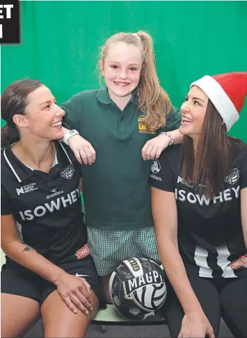  ?? Picture: ALISON WYND ?? HAVING A BALL: Madi Robinson (left) and Collingwoo­d teammate Sharni Layton present fan Jazmine Easton, 11, with an early Christmas present at Leopold Primary School.