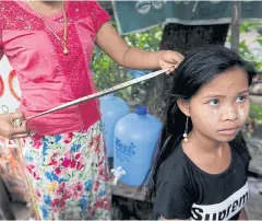  ??  ?? Zin Mar measures the length of the hair of a customer who is thinking of selling it.