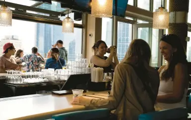  ?? GABRIELA BHASKAR/THE NEW YORK TIMES ?? Happy hour is on at the 5 O’Clock Somewhere Bar at the Margaritav­ille Resort last month in New York’s Times Square. As employees return to offices, some bars say their after-work happy hour crowds are now nearing pre-pandemic levels.