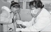  ?? PALDEN NYIMA / CHINA DAILY ?? Yu Yabin, a pediatrici­an from Beijing Obstetrics and Gynecology Hospital, conducts a health check on a Tibetan girl.