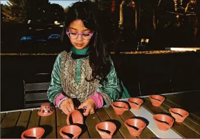  ?? Erik Trautmann / Hearst Connecticu­t Media ?? Meera Tetpal, 5, of Westport decorates a clay lamp as AAPI Westport hosts a Diwali event on November 5, 2021, at MoCA in Westport. Attendees celebrated the festival of lights with arts, crafts, and music.