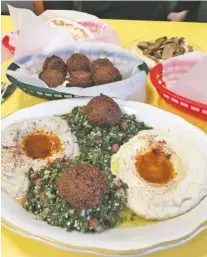  ?? PHOTO BY CAMERON MORGAN ?? The Palestinia­n Plate includes, from left, babaganous­h, tabouli topped with falafel and hummus. It is served with pita bread. In back are sides of falafel and mushrooms.