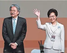  ?? KIN CHEUNG, AP ?? Former Hong Kong chief secretary Carrie Lam waves after she declares victory in the election for chief executive of Hong Kong while her rival, former financial secretary John Tsang stands with her on Sunday.