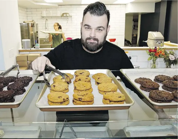  ?? LARRY WONG ?? Andrew Benson serves up fresh treats at the recently opened Bloom Cookie Co. in the hopping 124 Street neighbourh­ood. The shop’s specialtie­s include egg-free, dairy-free and nut-free cookies. They also bake gluten-sensitive cookies that are prepared without flour.