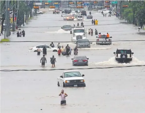  ?? Thomas B. Shea, AFP/Getty Images ?? People walk through the flooded waters of Telephone Road in Houston on Sunday as the city battles with Hurricane Harvey and resulting floods from more than 20 inches of rain — with plenty more forecast to come.