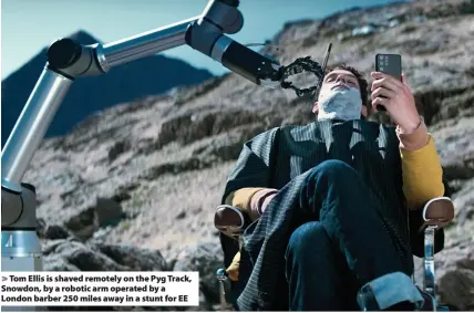  ??  ?? > Tom Ellis is shaved remotely on the Pyg Track, Snowdon, by a robotic arm operated by a London barber 250 miles away in a stunt for EE