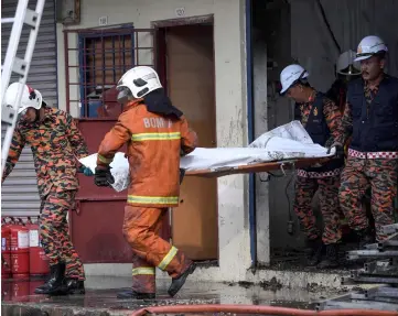  ?? — Bernama photo ?? Firefighte­rs remove the body of a victim from the two-storey shophouse yesterday.