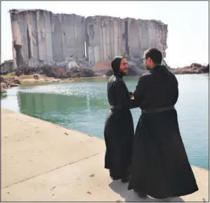  ??  ?? Priests talk Wednesday near towering grain silos that were gutted in the massive August 2020 explosion.