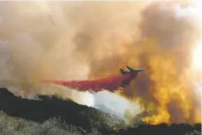  ?? RINGO H.W. CHIU/ASSOCIATED PRESS ?? An air tanker drops retardant on a wildfire Wednesday in Goleta, Calif. A wildfire raging through Southern California coastal mountains threatened ranches and rural homes and kept a major highway shut down as the fire-scarred state faced a new round of dry winds.