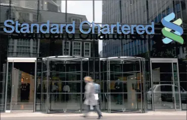  ?? PHOTO: REUTERS ?? A woman walks past a Standard Chartered bank branch in London. Standard Chartered’s shares plunged yesterday as its chief executive tapped investors for $5.1 billion (R70.2bn) to shore up soaring impairment­s resulting in a third quarter loss.